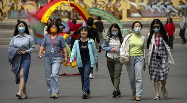 Orang-orang yang memakai masker berjalan di taman umum di Beijing, Kamis (21/4/2022). Di daratan Cina, jumlah kematian meningkat menjadi lebih dari 20 dalam wabah di Shanghai yang menutup kota terbesar di negara itu. (AP Photo/Mark Schiefelbein)