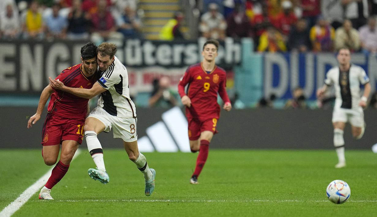 <p>Pemain Timnas Spanyol, Marco Asensio (kiri) berebut bola dengan pemain Jerman, Leon Goretzka dalam pertandingan Grup E Piala Dunia 2022 yang berlangsung di Al Bayt Stadium, Qatar, Senin (28/11/2022). (AP Photo/Julio Cortez)</p>
