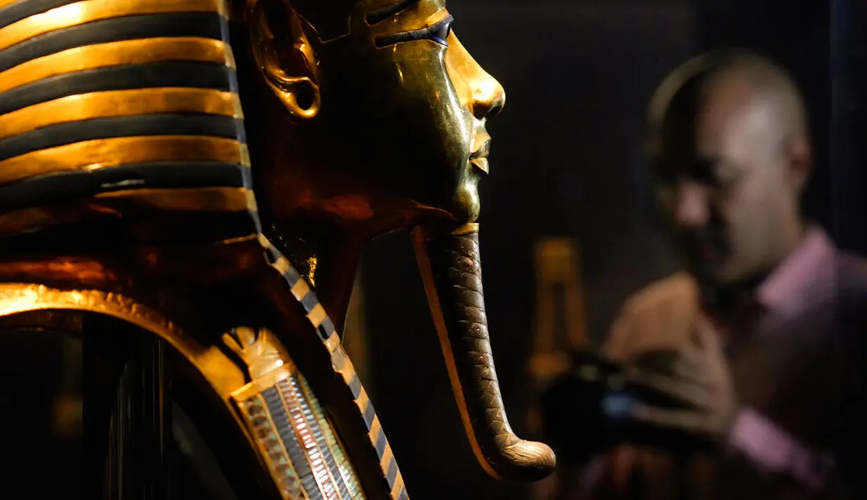 Seorang pria memfilmkan topeng emas Raja Tutankhamun saat perayaan untuk menghormati Hari Pariwisata Dunia dan peringatan 200 tahun Egyptology sebagai ilmu di Museum Mesir, Kairo, Mesir, 27 September 2022. (AP Photo/Amr Nabil)
