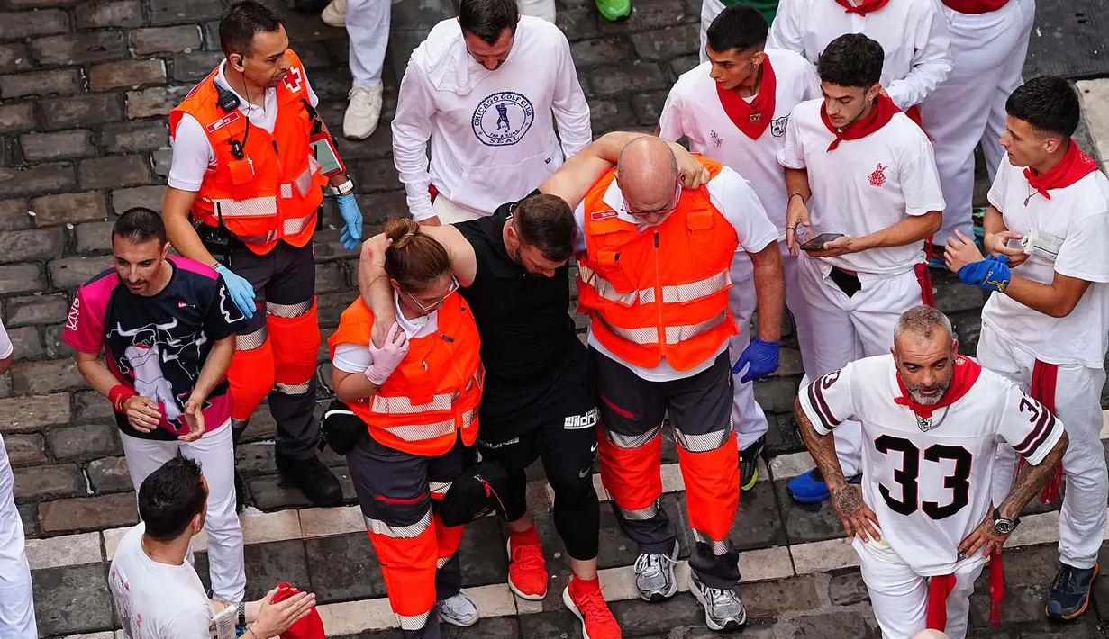 Tim medis membantu seorang peserta festival yang terluka setelah acara lari banteng ketiga di festival San Fermín di Pamplona, Spanyol, Kamis, 9 Juli 2026. (AP Photo/Miguel Oses)