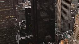 Asap membumbung dari bagian sudut atas gedung Trump Tower di New York, Senin (8/1). Petugas pemadam kebakaran New York City mengatakan api tersebut muncul dari sistem pemanas dan penyejuk udara gedung. (Jeff Levi via AP)