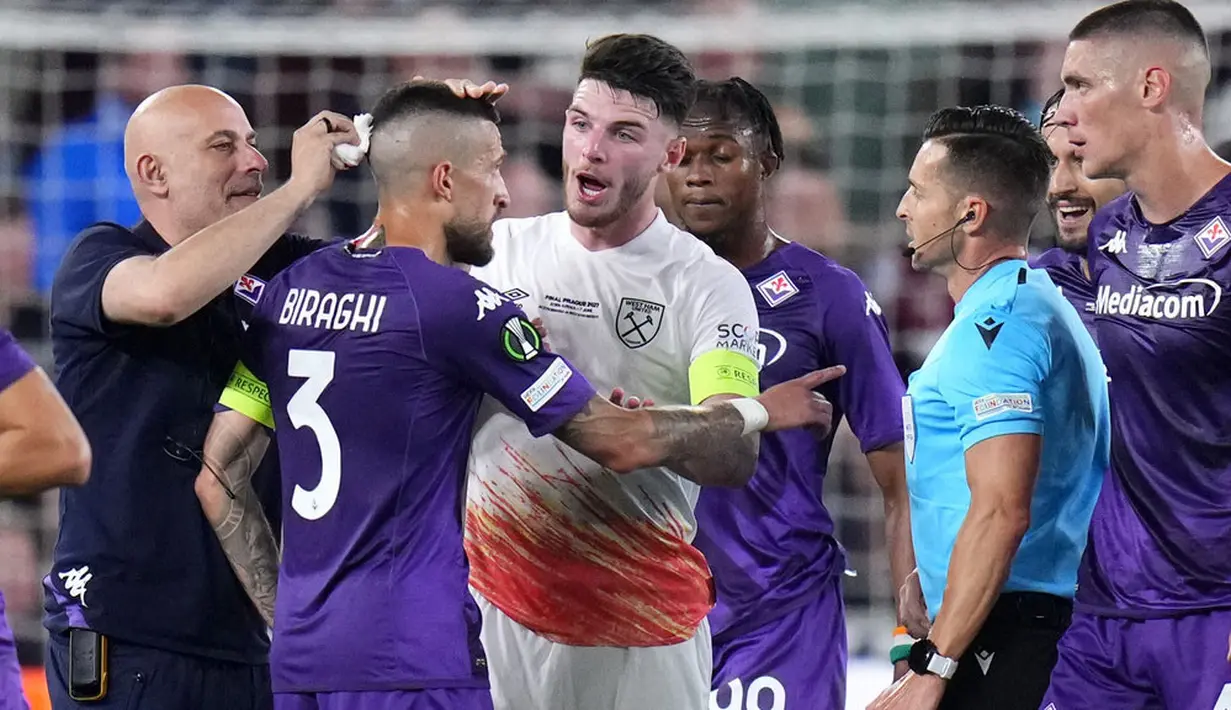 Pemain Fiorentina, Cristiano Biraghi, mendapat perawatan akibat menderita luka di bagian kepala setelah insiden pelemparan benda dari tribun suporter West Ham United pada laga final UEFA Europa Conference League di Stadion Eden Arena, Kamis (8/6/2023). Fiorentina takluk dengan skor 1-2. (AP Photo/Petr David Josek)