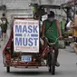 Seorang pria mengendarai becaknya dengan slogan untuk mengingatkan orang agar memakai masker untuk mencegah penyebaran virus corona di Manila, Filipina, Senin (26/4/2021). Infeksi COVID-19 di Filipina melonjak melewati 1 juta pada hari Senin dalam tonggak suram terbaru. (AP Photo/Aaron Favila)