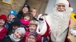 Seorang pria berpakaian Santa Claus berpose dengan anak - anak di kantor pos desa Himmelpfort, Jerman, (10/11/2015).  Sudah anak - anak dari 80 negara mengirim surat kepada Santa Claus. (REUTERS/Hannibal Hanschke)