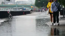 Orang-orang berjalan di tengah hujan di London, Rabu (17/8/2022). Setelah berminggu-minggu cuaca terik, yang telah menyebabkan kekeringan dan membuat tanah kering, peringatan badai petir kuning dari Kantor Meteorologi memperkirakan hujan lebat dan badai petir yang bisa melanda bagian Inggris dan Wales. (Victoria Jones/PA via AP)