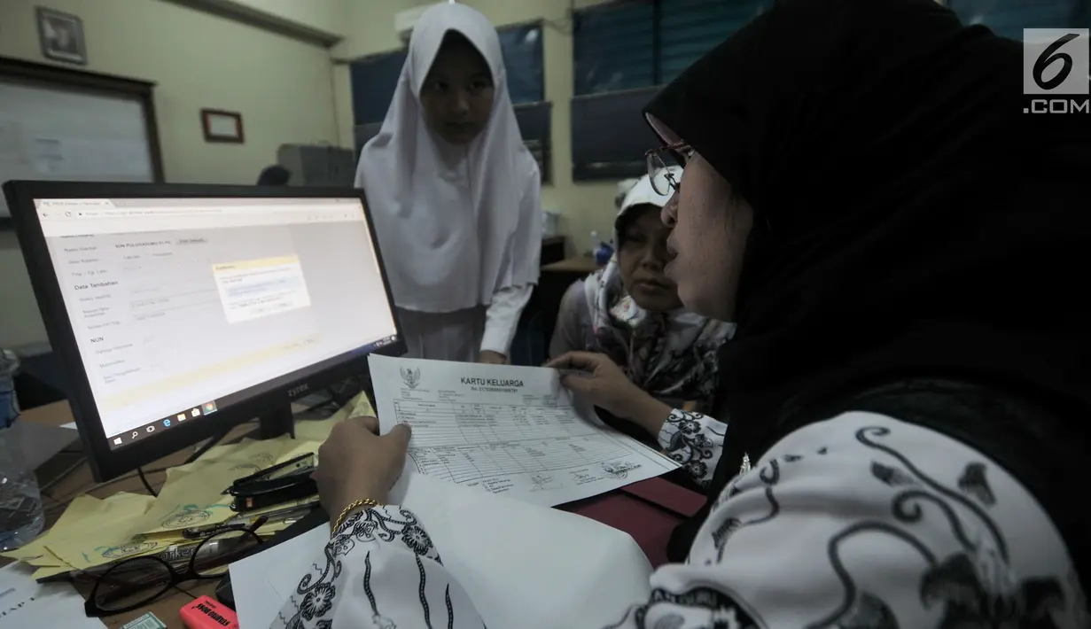Panitia pelaksana saat membantu salah satu pendaftar dalam proses pengambilan nomor token PPDB di SMPN 92, Jakarta, Senin (25/6). (Merdeka.com/Iqbal S Nugroho)