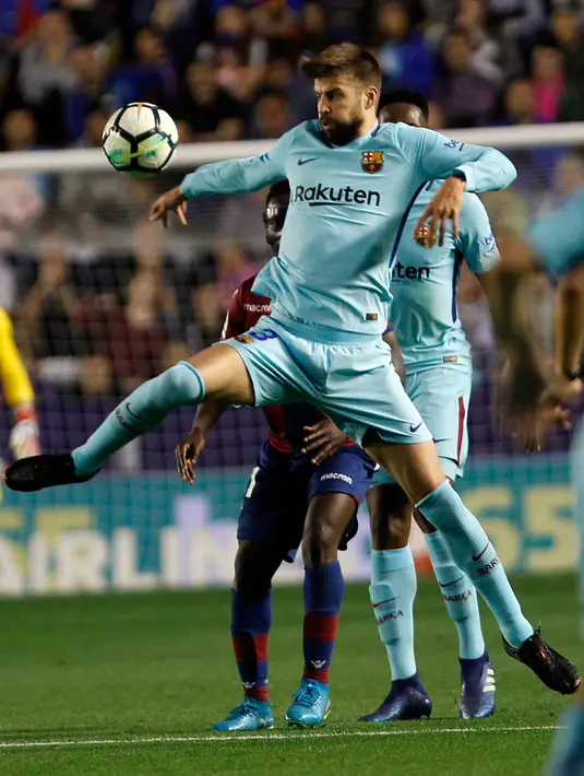 Pemain Barcelona Gerard Pique berebut bola dengan pemain Levante, Emmanuel Boateng pada jornada ke-37 La Liga di Estadio Ciudad de Valencia, Senin (14/5). Barcelona gagal menjaga rekor tak terkalahkan musim ini pada ajang La Liga Spanyol (AP/Alberto Saiz)