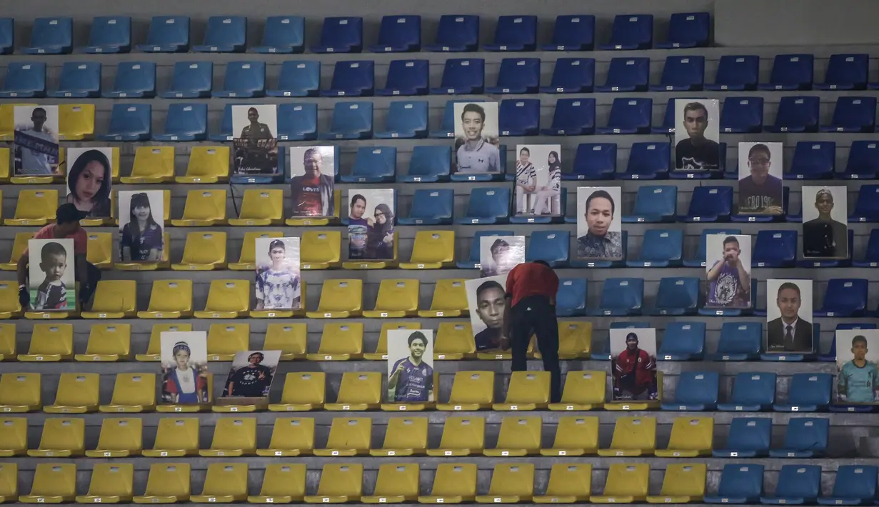 Sejumlah petugas melepas papan berwajah para fans Arema FC terlihat saat laga pekan kesebelas BRI Liga 1 2021/2022 antara Arema FC melawan Persebaya Surabaya di Stadion Manahan, Solo, Sabtu (06/11/2021). (Bola.com/Bagaskara Lazuardi)