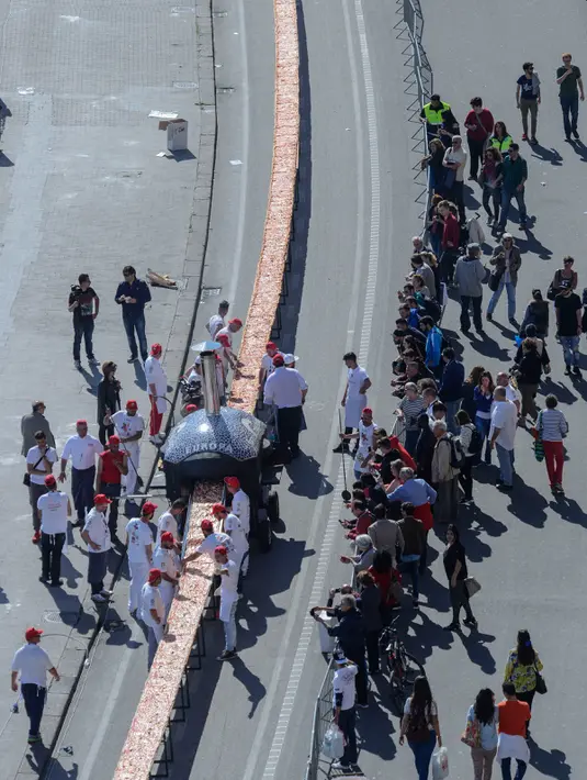 Warga melihat pembuatan pizza terpanjang, di sepanjang pinggir Laut Naples, Italia, 18 Mei 2016. Pembuatan pizza sepanjang 1 mil ini diharap dapat mengalahkan rekor dunia yang sebelumnya dicetak sepanjang 1.595 meter di Milan pada 2015 (Mario LAPORTA/AFP)