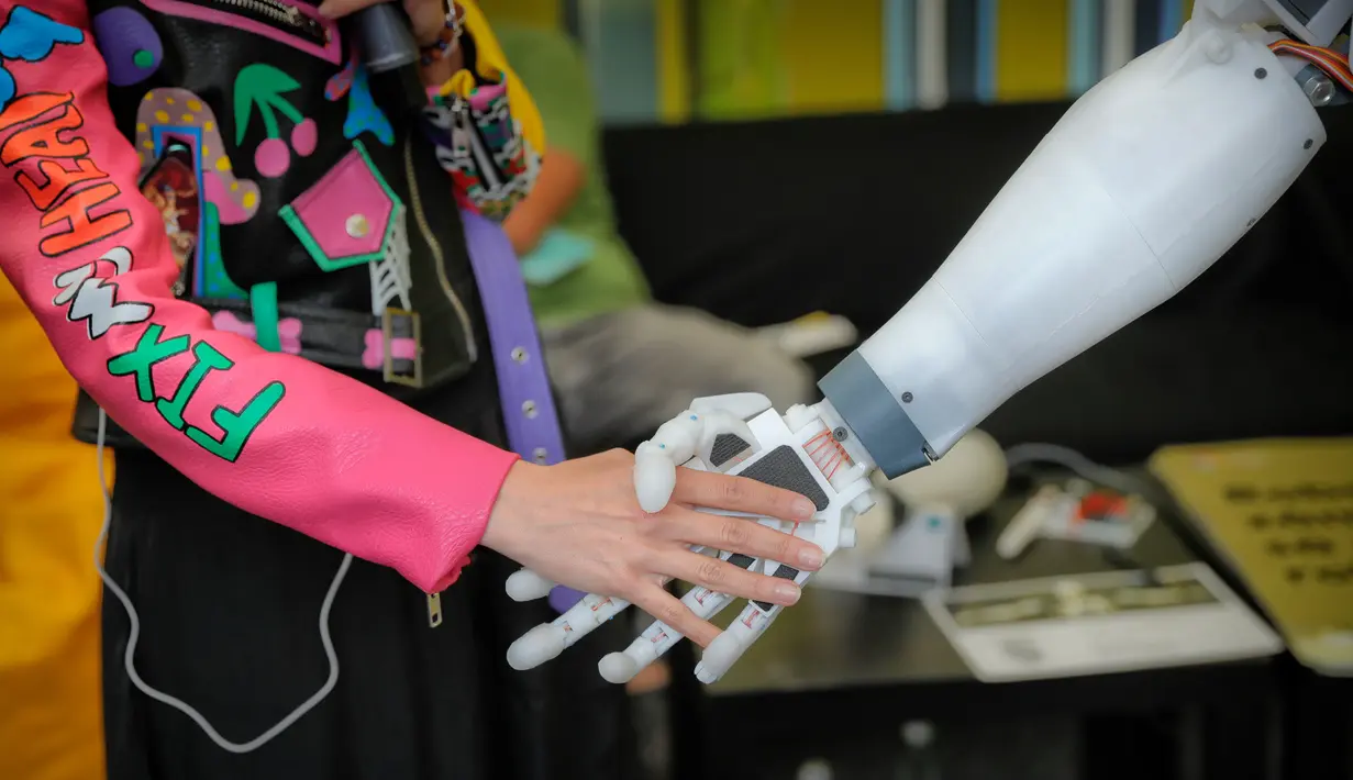 Seorang reporter berjabat tangan dengan robot InMoov rancangan Gael Langevin dalam pameran teknologi Bucharest, Romania (26/5). (AP Photo / Vadim Ghirda)