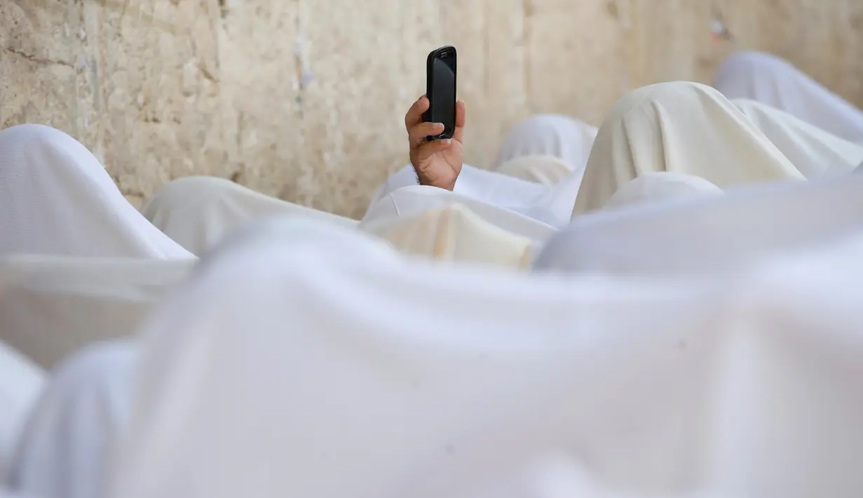 Seorang umat Yahudi menggunakan ponselnya merekam prosesi doa massal di tembok ratapan di Kota Tua Yerusalem selama hari libur Sukkot, (19/10). Perayaan Sukkot ini  merupakan perayaan pengucapan syukur bagi Israel atas hasil panen. (REUTERS/Baz Ratner)