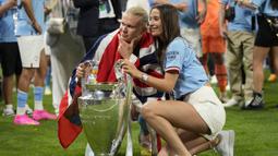 Striker Manchester City, Erling Haaland bersama sang kekasih, Isabel Haugseng Johansen berpose dengan trofi Liga Champions dalam perayaan kemenangan atas Inter Milan pada laga Final Liga Champions 2022/2023 di Ataturk Olympic Stadium, Istanbul, (10/6/2023). Gelar ini menjadi yang pertama baginya dan dilengkapi dengan gelar top skor dengan torehan 12 gol. (AP Photo/Francisco Seco)