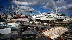 Perahu-perahu udang yang datang dari jauh ke bawah pantai duduk di atas sisa-sisa taman rumah mobil setelah diterjang Badai Ian di Pulau San Carlos, Pantai Fort Myers, Florida, Rabu (5/10/2022). Puing-puing berserakan di pantai, perahu terdampar dan beberapa bangunan tidak tersisa sama sekali. (AP Photo/Rebecca Blackwell)