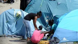 Sejumlah wanita berbincang di dekat tenda yang didirikan di sebuah kamp sementara di sekitar pelabuhan Calais, Prancis, Minggu (2/8/2015). Sebelumnya, ratusan imigran memaksa masuk Prancis melalui Terowongan Channel. (AFP PHOTO/FRANCOIS LO PRESTI)