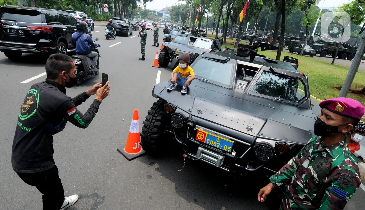 Warga memotret anak di kendaraan taktis TNI yang dipamerkan di depan Istana Merdeka, Jakarta, Senin (4/10/2021). Ratusan alat utama sistem persenjataan (Alutsista) TNI dipamerkan sepanjang pinggir jalan sekeliling kawasan Monas dalam rangka peringatan HUT ke-76 TNI. ​(merdeka.com/Arie Basuki)