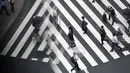 Orang-orang memakai masker untuk membantu mencegah penyebaran virus corona berjalan di penyeberangan pejalan kaki di Tokyo, (23/9/2020). Badai tropis di Samudra Pasifik perlahan mendekati wilayah Tokyo pada hari Rabu. (AP Photo/Eugene Hoshiko)