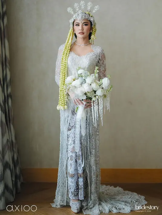 Saat akad nikah, Mahalini tampil dalam balutan busana adat Sunda. Ia terlihat begitu anggun dalam balutan kebaya putih karya desainer Asky Febrianti. Aksen brokat salur dan payet pada kebayanya memberikan impresi elegan. Dipadukan dengan siger sunda rancangan Rinaldy Yunardi. [@axioo]