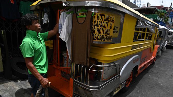 Pengemudi menggantung baju di jeepney miliknya yang berfungsi sebagai rumah sementara di sepanjang jalan di Manila, 12 Agustus 2020. Angkutan ikonik di Filipina itu belum dapat mengangkut penumpang sejak Maret akibat lockdown Covid-19 yang membuat jutaan orang kehilangan pekerjaan. (Ted ALJIBE/AFP)