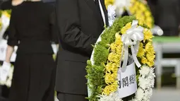 Perdana Menteri Jepang Shinzo Abe membawa karangan bunga pada saat upacara peringatan 70 tahun jatuhnya bom atom di Hiroshima, Jepang (6/8/2015). 140.000 penduduk Jepang tewas akibat Bom Atom. (REUTERS/Kyodo)