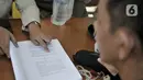 Petugas menunjukkan sanksi hukuman pelanggar PSBB yang tertuang dalam undang-undang di area Pasar Kramat Jati, Jakarta, Rabu (17/6/2020). (merdeka.com/Iqbal S. Nugroho)