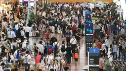 Puluhan calon penumpang berkerumun di lobi keberangkatan Bandara Haneda di Tokyo, Senin (22/8). Topan Mindulle yang bergerak menuju Tokyo menyebabkan hampir 400 penerbangan dibatalkan akibat hujan lebat dan angin kencang. (Jiji Press/AFP)