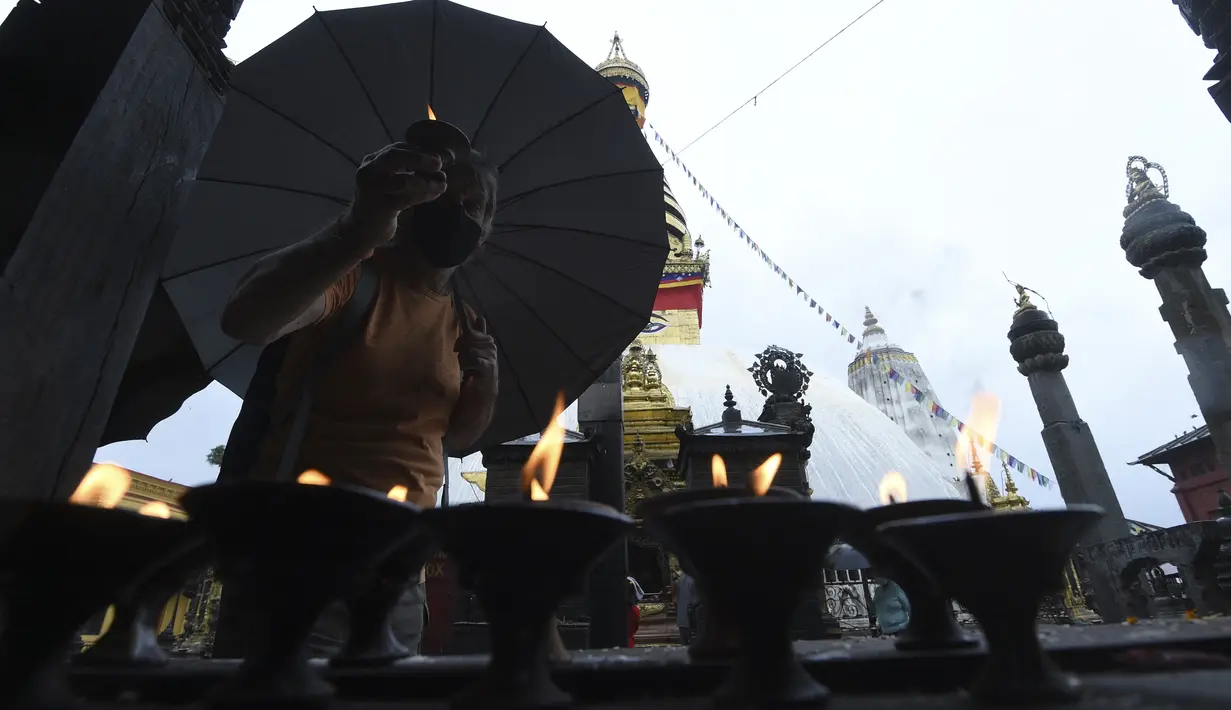 Umat Buddha berdoa di Stupa Swayambhunath pada acara Festival Buddha Purnima, selama lockdown virus corona yang diberlakukan pemerintah, di Kathmandu, Nepal, Rabu (26/5/2021). Waisak disebut juga Buddha Purnima atau Buddha Jayanti. (PRAKASH MATHEMA / AFP)