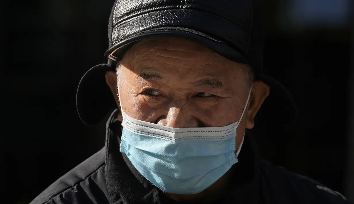 Seorang pria mendongak sambil mengenakan topeng di jalan Beijing, China, Selasa (14/12/2021). Media pemerintah China mengatakan Senin, 13 Desember 2021, kasus pertama varian omicron COVID-19 telah terdeteksi di daratan negara di kota Tianjin di sebelah timur Beijing. (AP Photo/Ng Han Guan)