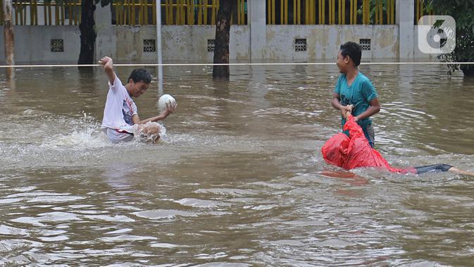 Warga terjatuh saat melintasi banjir yang merendam Jalan Pondok Raya Gede, Jakarta Timur, Selasa (25/2/2020).  Sejumlah ruas jalan tergenang dan akses ke beberapa wilayah terputus, salah satunya Jalan Pondok Raya Gede. (Liputan6.com/Herman Zakharia)