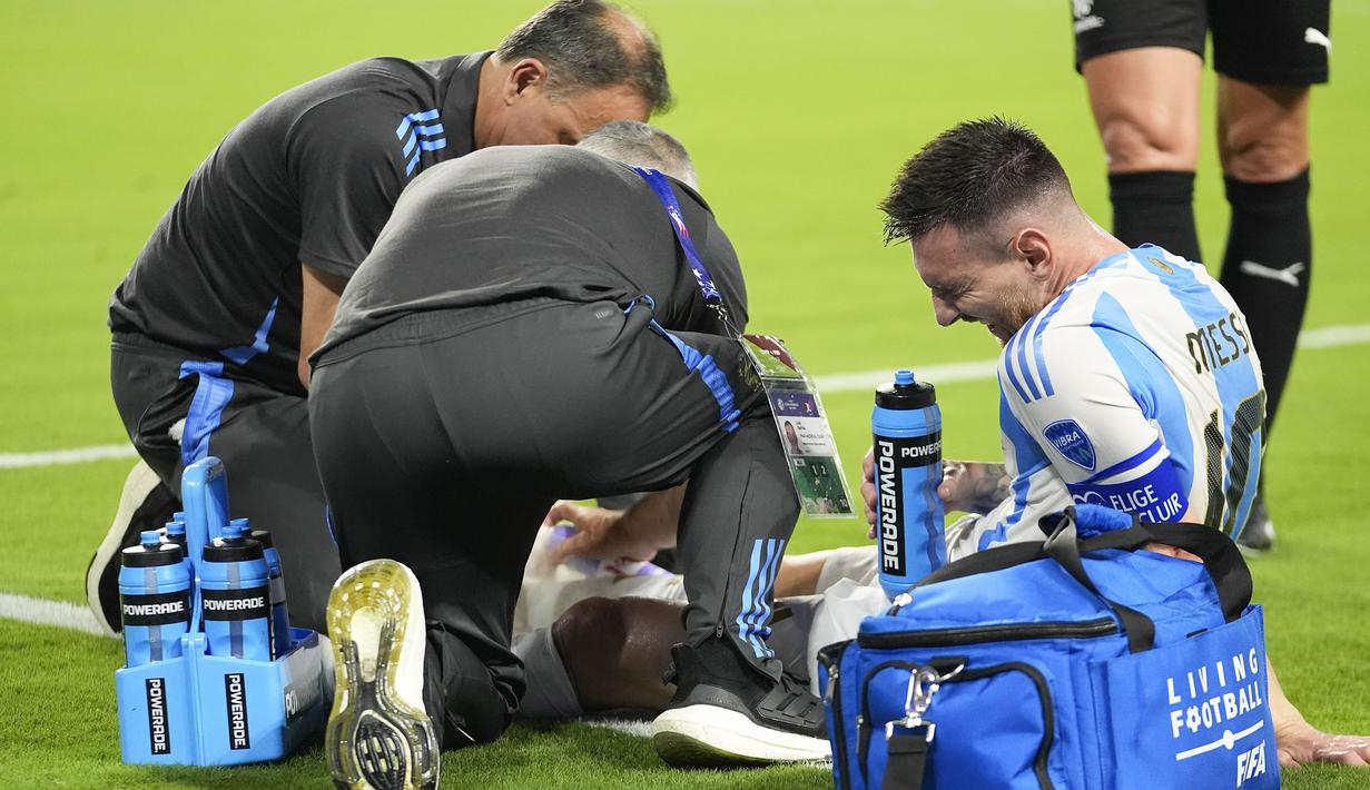 Kapten Timnas Argentina, Lionel Messi mendapat perawatan tim medis usai mengalami cedera saat menghadapi Timnas Kolombia pada laga final Copa America 2024 di Hard Rock Stadium, Florida, Amerika Serikat, Minggu (14/7/2024). (AP Photo/Rebecca Blackwell)