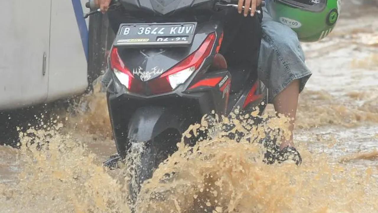 Seorang pengendara sepeda motor saat menerobos genangan banjir yang merendam Jalan Raya Bogor di depan Pasar Induk Kramat Jati.