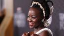 Lupita Nyong'o berpose saat menghadiri pemutaran perdana film Black Panther: Wakanda Forever" di Dolby Theatre di Los Angeles pada Rabu, 26 Oktober 2022. Rambut brunette-nya ditata dengan twist updo yang beraksen dengan ikat kepala yang terbuat dari kerang. (Jesse Grant/Getty Images for Disney/AFP)