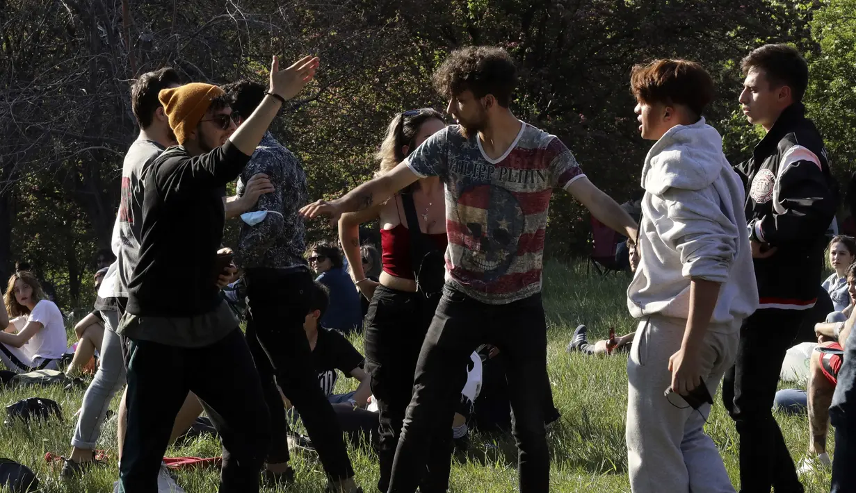 Para pria berdebat saat orang-orang menikmati cuaca cerah di taman, beberapa jam setelah berakhirnya lockdown, di Ankara, Senin (17/5/2021). Saat ini infeksi di Turki telah turun menjadi kurang dari 15 ribu per hari dari sekitar 40 ribu pada awal lockdown pada akhir April. (AP Photo/Burhan Ozbilici)