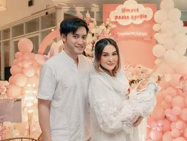 Dalam momen akikah sang anak, Kevin Aprilio dan Vicy Melanie tampil selaras dengan busana warna putih. Kevin gagah dengan baju koko, sementara Vicy Melanie anggun dengan dress dan memakai hijab yang menutupi sebagian rambutnya. Lahir pada 5 Oktober 2024, Baby Kimova di akikah ketika usianya 1,5 bulan. Dikaruniai anak pertama setelah 4 tahun, kebahagiaan terpancar jelas di wajah pasangan ini. (Liputan6.com/IG/@vicymelanie)