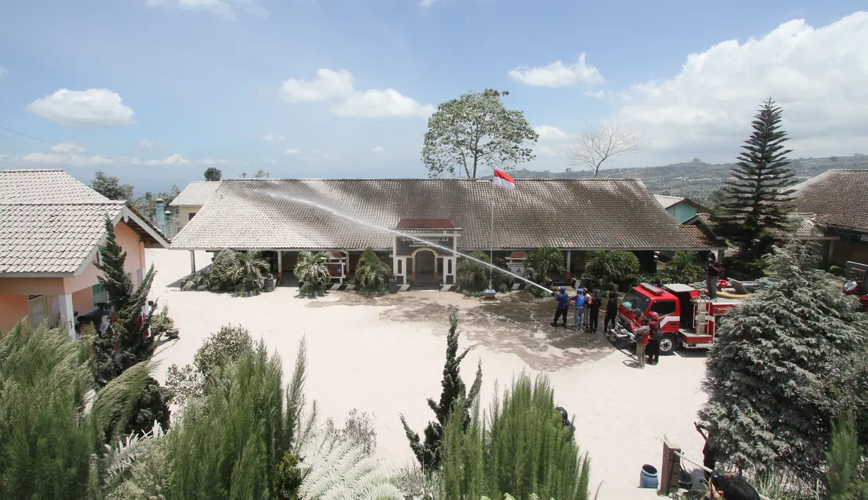 Petugas pemadam kebakaran membersihkan sekolah dari abu setelah Gunung Merapi meletus di Boyolali, Jawa Tengah pada 13 Maret 2023. Gunung Merapi yang terletak di perbatasan Jawa Tengah dan Daerah Istimewa Yogyakarta (DIY) mengeluarkan guguran awan panas pada Sabtu siang (11/3/2023). Akibat erupsi tersebut menyebabkan sejumlah daerah di Kabupaten Boyolali yang terletak di lereng Gunung Merapi diguyur hujan abu. (AFP/Dika)