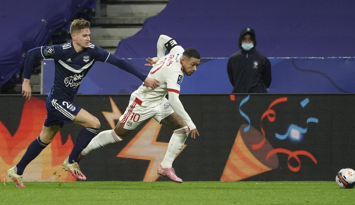 Striker Lyon, Memphis Depay (kanan) dan gelandang Bordeaux, Toma Basic berlari memburu bola dalam laga lanjutan Liga Prancis 2020/21 pekan ke-22 di Groupama Stadium, Jumat (29/1/2021). Lyon menang 2-1 atas Bordeaux. (AP/Laurent Cipriani)