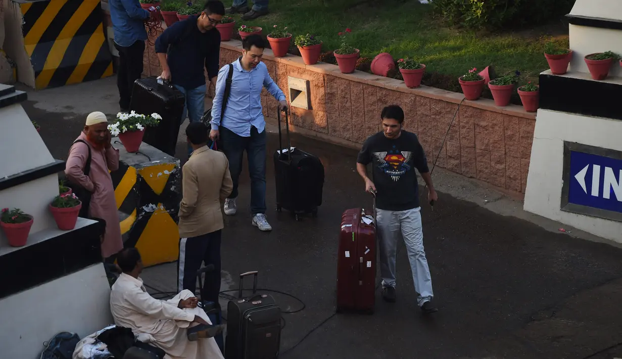 Para tamu berkumpul di luar sebuah hotel mewah yang mengalami kebakaran di Karachi, Pakistan, Senin (5/12). Kebakaran bermula di sebuah dapur di lantai dasar hotel Regent Plaza dan membuat para tamu di lantai-lantai atas terjebak. (RIZWAN Tabassum/AFP)