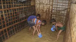 Anak-anak pengungsi Rohingya mengeluarkan air banjir dari rumah mereka di kamp pengungsi Rohingya di Kutupalong, Bangladesh (28/7/2021). Ribuan pengungsi kehilangan tempat tinggal akibat banjir tersebut. (AP Photo/Syafiqur Rahman)