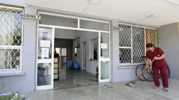 Seorang wanita mengepel pintu masuk kampus mahasiswa yang akan menampung warga Afghanistan, di Tirana, Albania, Rabu (18/8/2021).  Albania sedang mempersiapkan kedatangan warga Afganistan yang bekerja dengan pasukan penjaga perdamaian Barat yang terancam Taliban. (AP Photo/Franc Zhurda)