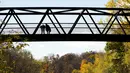 Orang-orang memandangi Sungai Kredit di sebuah jembatan, di antara warna-warni musim gugur di Mississauga, Ontario, pada Kamis, 27 Oktober 2022. (Nathan Denette/The Canadian Press via AP)