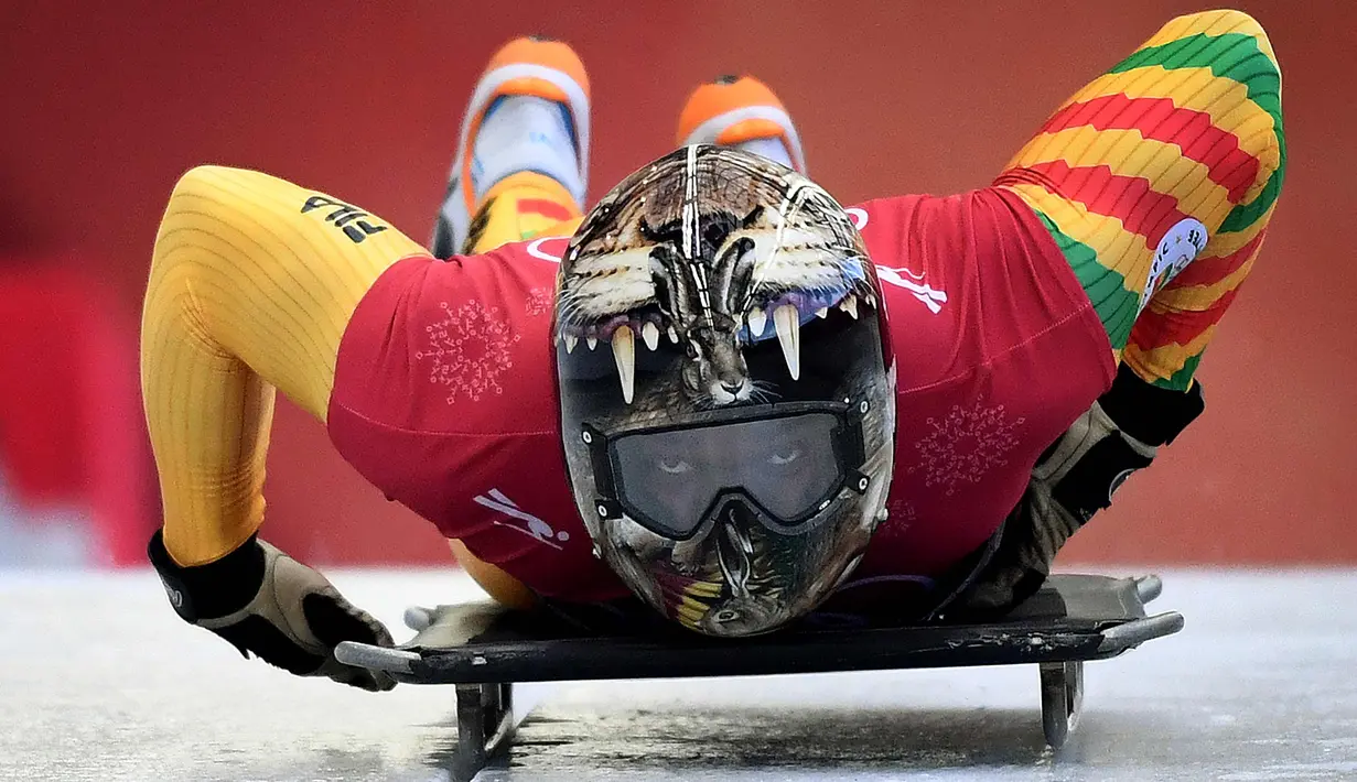 Atlet balap kereta salju, Akwasi Frimpong dari Ghana memulai sesi latihan pada Olimpiade Musim Dingin Pyeongchang 2018 di Olympic Sliding Center di Pyeongchang, Korsel (21/2). Akwasi memakai helm dengan design kepala harimau. (AFP Photo/Mark Ralston)