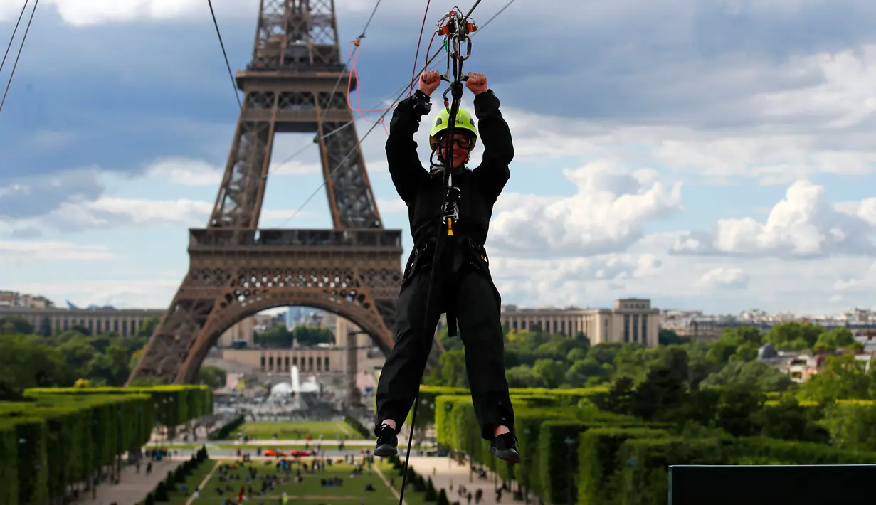 Pengunjung meluncur dengan seutas tali saat menjajal Zip Line dari lantai dua Menara Eiffel di atas taman Champ de Mars, Paris, Selasa (28/5/2019). Lintasan ini memungkinkan traveler untuk meluncur melintasi satu tempat ke tempat lainnya menggunakan tali dan alat olahraga outdoor. (AP/Francois Mori)