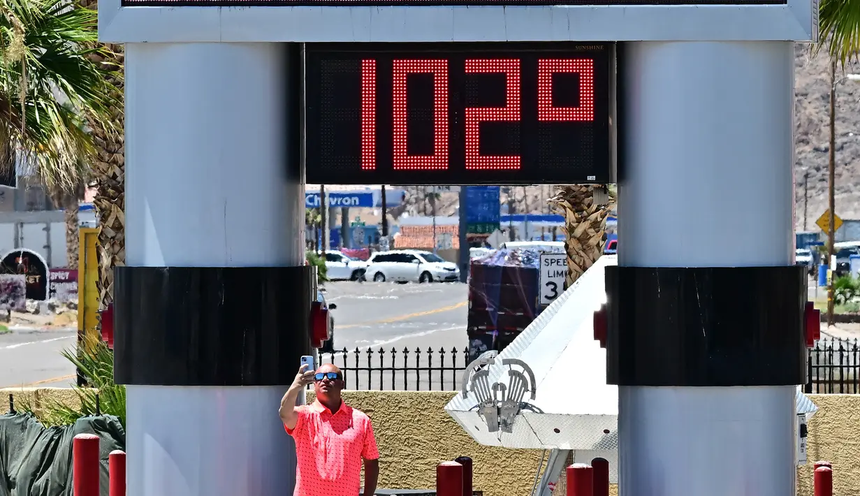 Seorang pria mengambil swafoto di samping termometer yang menunjukkan suhu 102 derajat celcius di Baker, California pada tanggal 11 Juli 2023, di tengah-tengah gelombang panas. (Photo by Frederic J. BROWN / AFP)