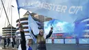 Dua orang fans Manchester City mengibarkan bendera klub sambil menyalakan flare merayakan keberhasilan timnya memastikan merebut gelar juara Liga Inggris 2020/2021 di luar Etihad Stadium, Selasa (11/5/20221) sesaat setelah kekalahan Manchester United 1-2 oleh Leicester City. (AP/Jon Super)