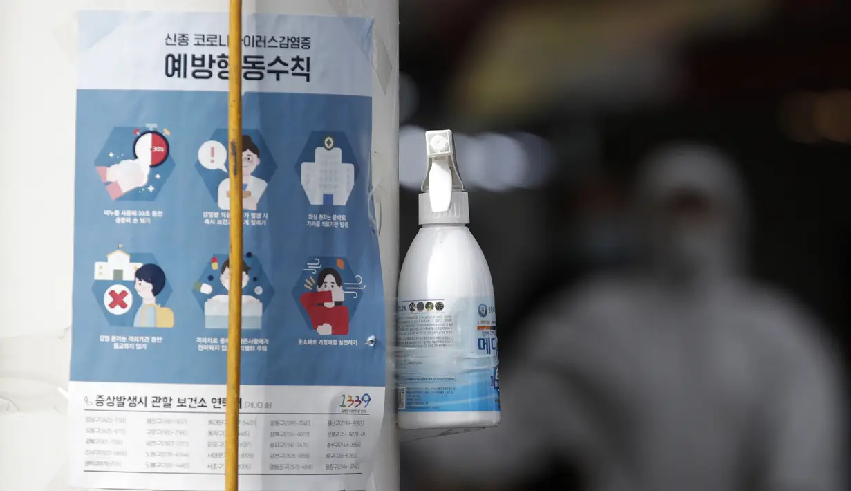 Botol cairan pembersih tangan disediakan di sisi jalan untuk warga di sebelah pemberitahuan tentang tindakan pencegahan COVID-19 di depan pasar di Seoul, Korea Selatan (26/2/2020). Cairan pembersih berbasis alkohol bisa membunuh virus yang kemungkinan berada di tangan. (AP Photo/Lee Jin-man)