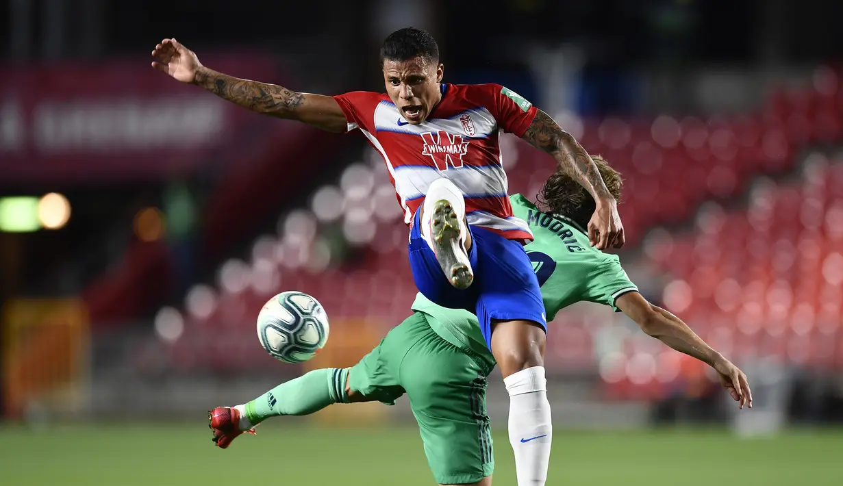 Gelandang Real Madrid, Luka Modric, berebut bola dengan striker Granada, Fede Vico, pada laga lanjutan La Liga pekan ke-36 di di Estadio Nuevo Los Carmenes, Selasa (14/7/2020) dini hari WIB. Real Madrid menang 2-1 atas Granada. (AP/Jose Breton)