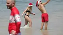 Topi Santa, jumper bertema Natal, dan bikini merah terlihat sejauh mata memandang di sepanjang pantai yang terkenal ini.  (AP Photo/Rick Rycroft)