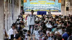 Panitia membagikan nasi kotak jelang buka puasa bersama di Masjid Istiqlal, Jakarta, Senin (6/5/2019). Kaum perempuan dan anak-anak duduk terpisah dengan lelaki. (Liputan6.com/Faizal Fanani)
