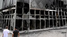 Dua pria melihat fasad Hotel du ville yang hangus dan terbakar di Garges-les-Gonesse, utara Paris, menyusul kerusuhan dua hari setelah seorang remaja 17 tahun ditembak di dada oleh polisi dari jarak dekat di Nanterre, pinggiran barat Paris, pada 29 Juni 2023. (Photo by Bertrand GUAY / AFP)