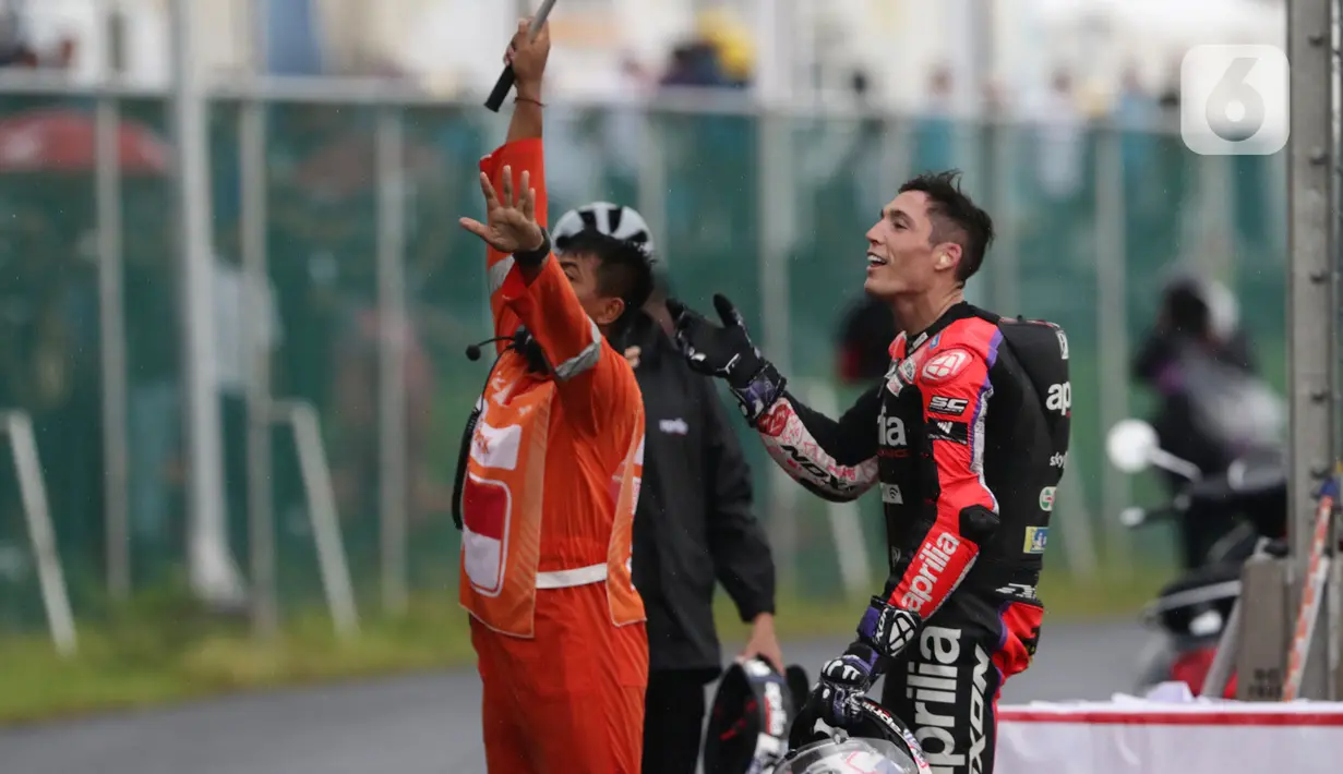 Pembalap Aprilia Racing, Aleix Espargaro (kanan) bersiap melemparkan helmnya ke penonton usai MotoGP seri Pertamina Mandalika International Street Sirkuit, NTB, Minggu (20/3/2022). Aksi ini untuk menepati janjinya setelah meraih sejuta pengikut akun instagramnya. (Liputan6.com/Helmi Fithriansyah)