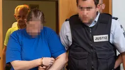 Terdakwa Berrin T (kiri) memasuki ruangan sebelum sidang putusan di pengadilan distrik di Freiburg, Jerman, Selasa (7/8). Berrin dan suami divonis penjara 12 dan 12,5 tahun. (THOMAS KIENZLE/AFP)